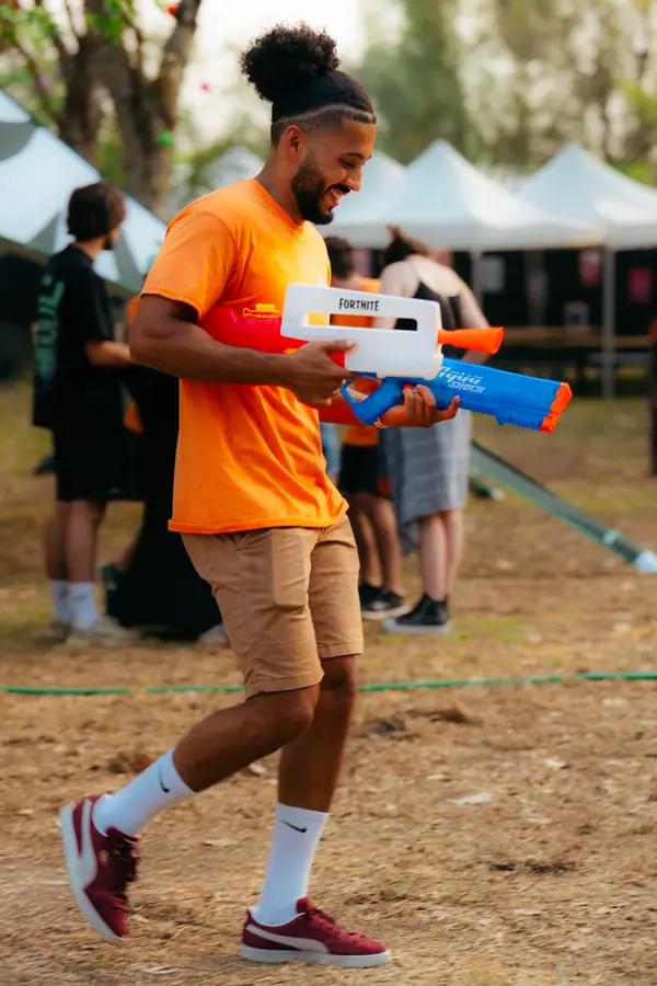 Bénévole en t-shirt orange avec un pistolet à eau pendant le Belfield Festival 2026