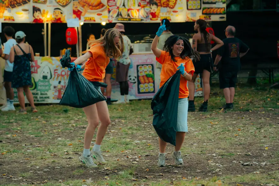 Deux bénévoles dansent en ramassant les déchets devant les food trucks du Belfield Festival 2026