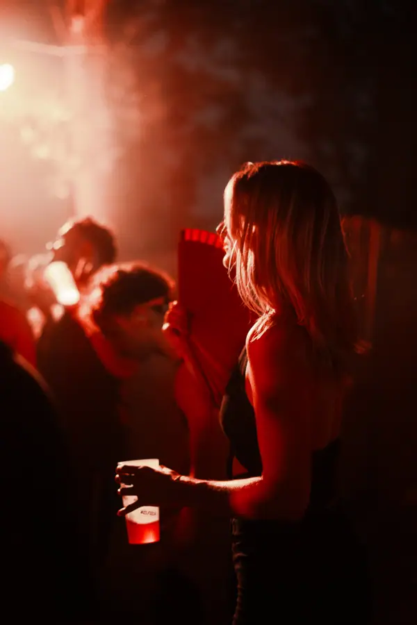 Festivalière gobelet à la main dans la fumée rouge du Belfield Festival 2026